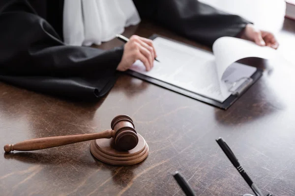 Selective focus of wooden gavel near cropped judge and clipboard with verdict — Photo de stock