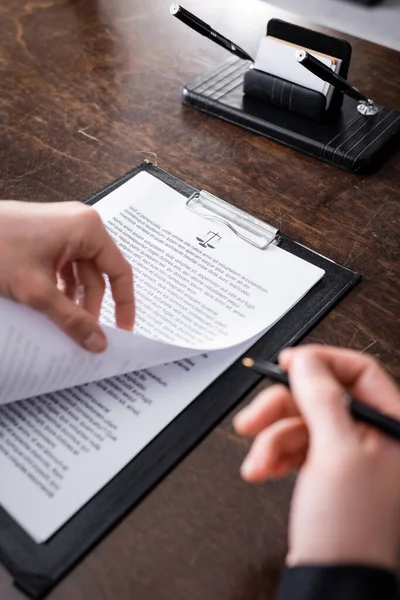 Partial view of prosecutor with pen near lawsuit on clipboard — Stock Photo