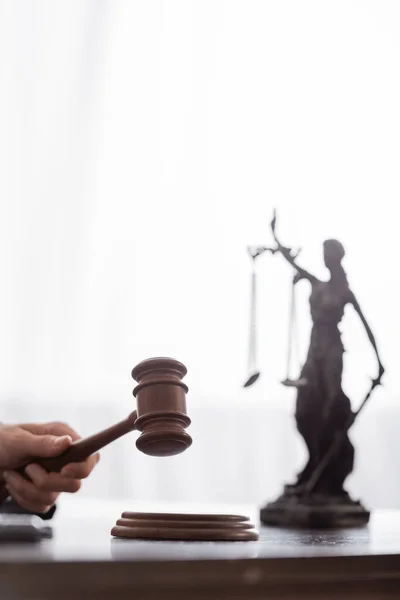 Partial view of judge with wooden gavel near blurred themis statue — Stockfoto