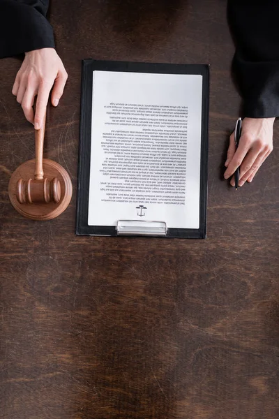 Top view of cropped judge holding gavel and pen near verdict on clipboard — Stockfoto