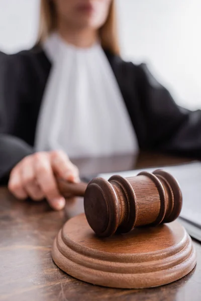 Close up view of wooden gavel in hand of cropped judge on blurred background — Fotografia de Stock