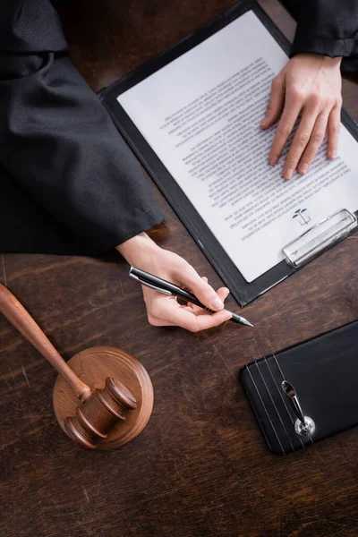 Top view of cropped prosecutor with pen near lawsuit and gavel — Stock Photo