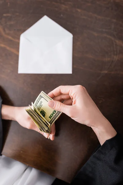 Top view of cropped judge counting money near blurred envelope — стоковое фото