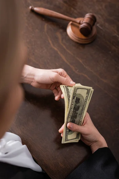 Partial view of prosecutor counting money on blurred foreground — Stock Photo