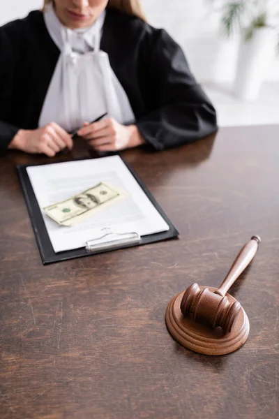 Selective focus of gavel near lawsuit, dollars and cropped judge on blurred background — Stock Photo