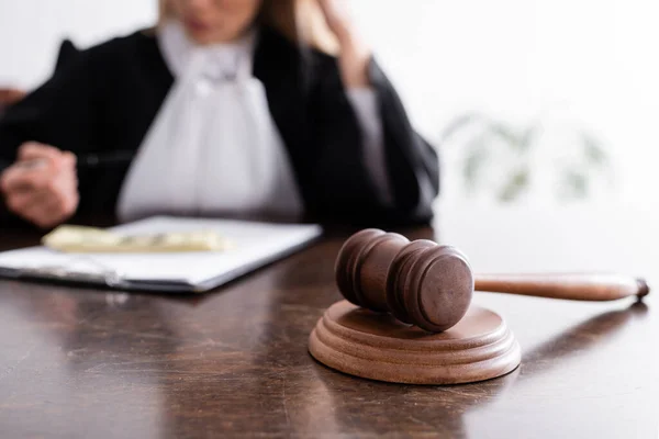 Selective focus of wooden gavel near cropped prosecutor and money on blurred background — Fotografia de Stock