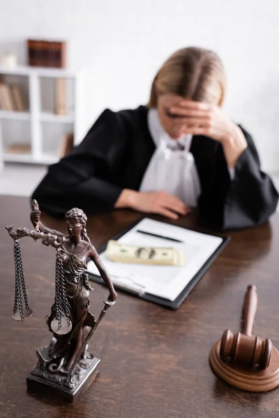 Depressed prosecutor sitting near bribe, lawsuit and themis statue - foto de stock