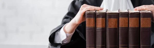 Cropped view of prosecutor near collection of books, banner — Stock Photo