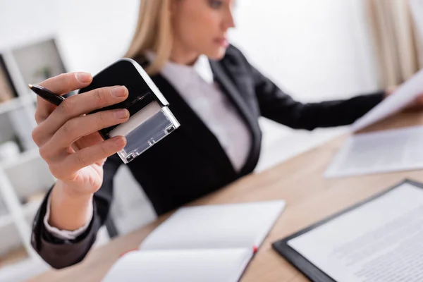 Selective focus of office stamp in hand of notary working on blurred background — Foto stock