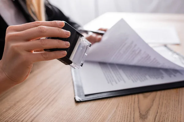 Selective focus of stamper in hand of cropped notary near blurred contract — Photo de stock