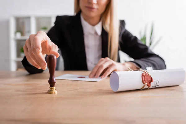 Partial view of burred notary taking stamper near rolled contract with wax seal — Stock Photo