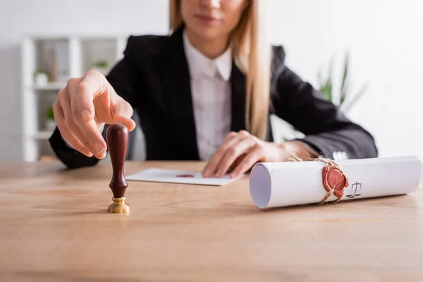 Partial view of burred notary taking stamper near rolled contract with wax seal - foto de stock