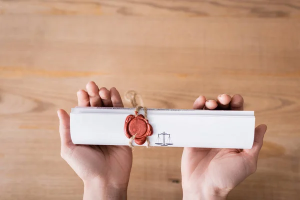 Top view of cropped lawyer holding rolled contract with wax seal — стоковое фото