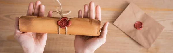 Partial view of notary holding rolled craft paper with wax seal and rope, banner — Stock Photo