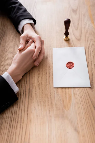 Partial view of lawyer near stamper and envelope sealed with wax on wooden desk — Fotografia de Stock