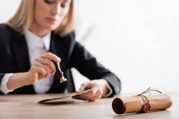 Selective focus of rolled contract with wax seal near notary with stamper on blurred background — Stock Photo