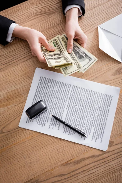 Top view of cropped lawyer counting money near contract and stamper on wooden desk — Stock Photo