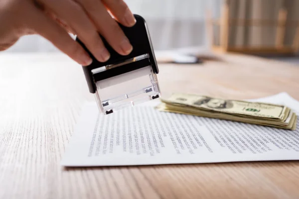 Cropped view of lawyer holding stamper near contract and dollar banknotes — Photo de stock