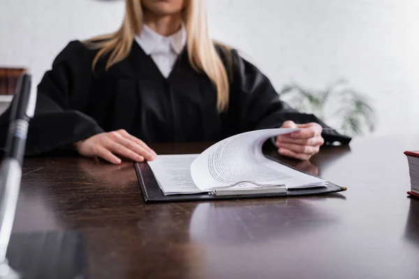 Ausgeschnittene Ansicht des Staatsanwalts im schwarzen Mantel, der mit Papieren auf verschwommenem Hintergrund arbeitet — Stockfoto