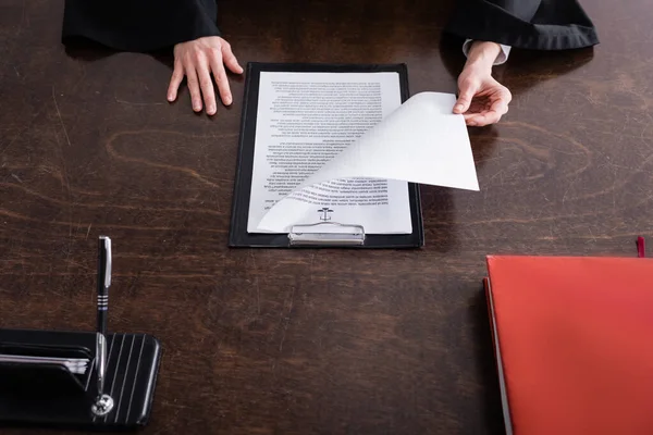 Partial view of prosecutor near clipboard with lawsuit on desk — Fotografia de Stock