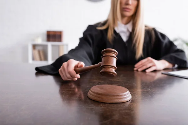 Cropped view of judge holding wooden gavel on blurred background — Foto stock