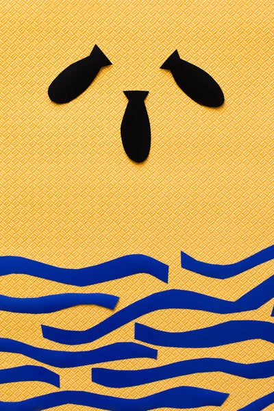 Вид сверху бумажных бомб и картонного моря на текстурированном желтом фоне — стоковое фото