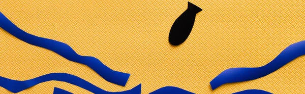 Top view of paper bomb near abstract carton sea on textured yellow background, banner — Stock Photo