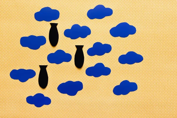 Vista superior de nubes de cartón y bombas de papel sobre fondo amarillo texturizado - foto de stock