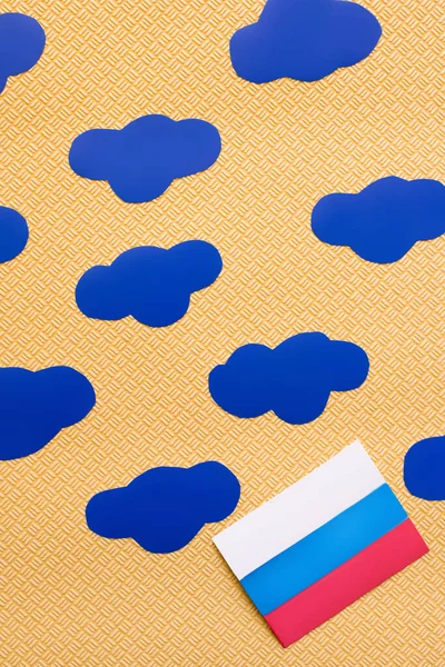 Draufsicht der russischen Flagge und Papierwolken auf strukturiertem gelben Hintergrund, Krieg in der Ukraine Konzept — Stockfoto