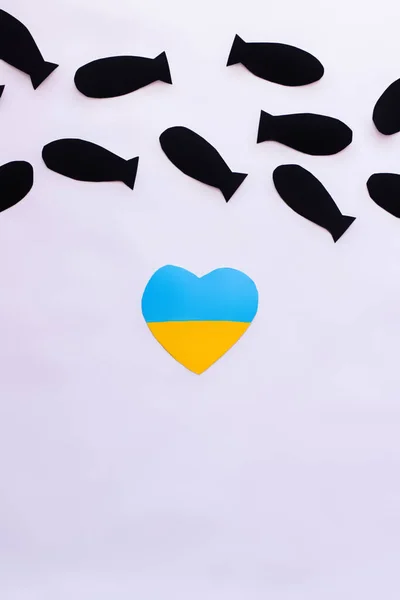 Vue du dessus du drapeau ukrainien en forme de coeur sous des bombes en papier sur fond blanc — Photo de stock