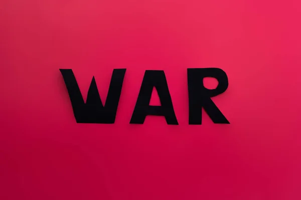 Vista superior de las letras de guerra de papel sobre fondo rojo - foto de stock