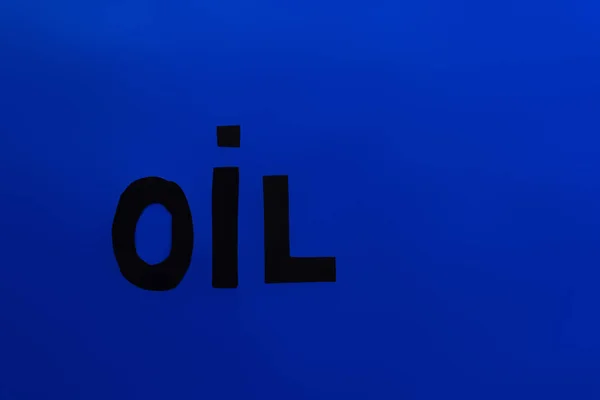 Top view of paper oil word on blue background — Stock Photo