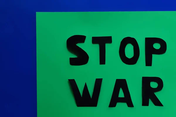 Top view of stop war paper lettering on green and blue background — Stock Photo