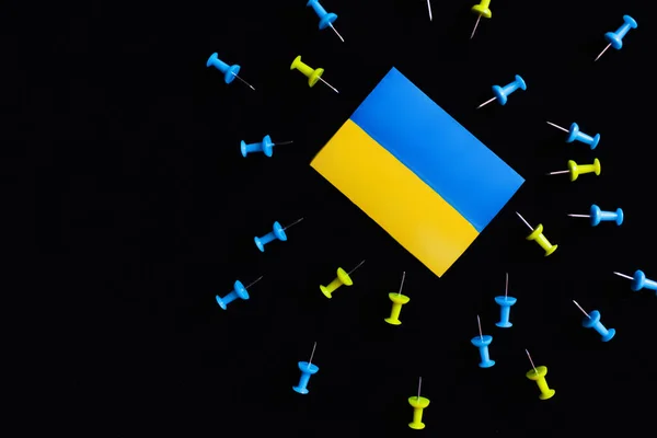 Top view of ukrainian flag near push pins isolated on black — Stock Photo