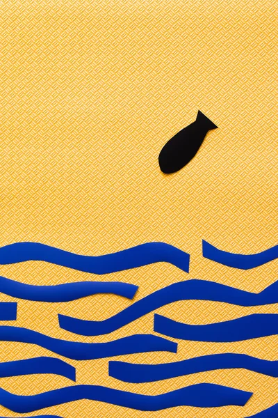 Вид сверху бумажной бомбы над картонным синим морем на фактурном желтом фоне, война в концептуальном виде — стоковое фото