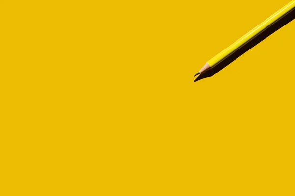 Top view of sharp pencil on yellow background — стоковое фото
