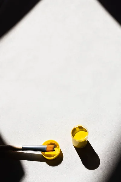 Vue de dessus de la peinture jaune près du pinceau sur blanc — Photo de stock