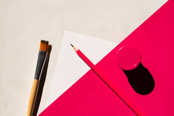 Top view of paintbrush, pencil and jar with paint on white and pink — Stock Photo