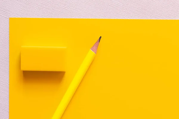 Top view of pencil near eraser on yellow and white — стоковое фото