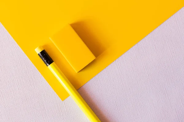 Top view of pencil and eraser on yellow and white — Stock Photo