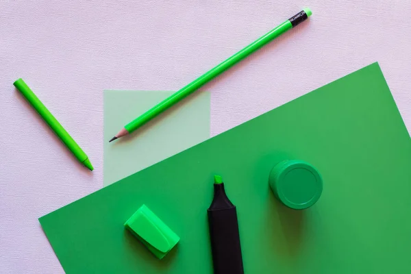 Draufsicht auf Bleistift, Buntstift, Glas mit Farbe und Filzstift auf grün und während — Stockfoto