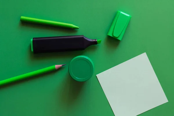 Vue du haut du crayon, du crayon, du pot avec de la peinture et du stylo marqueur près de la note de papier sur vert — Photo de stock