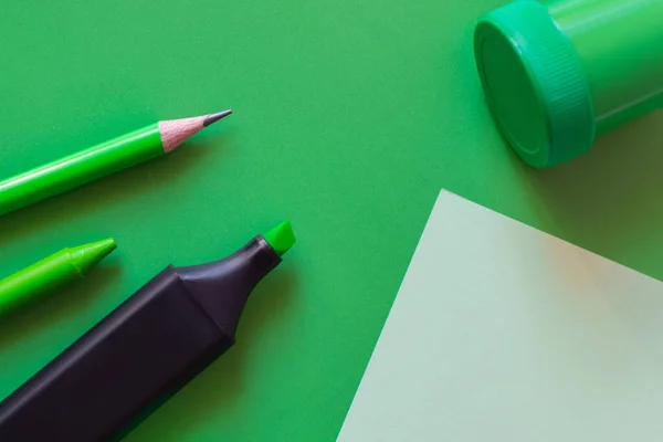 Top view of crayon, pencil, jar with paint and marker pen near paper note on green — Stock Photo