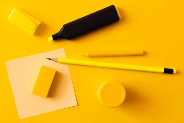 Top view of stationery and marker pen near paper note on yellow — Stock Photo