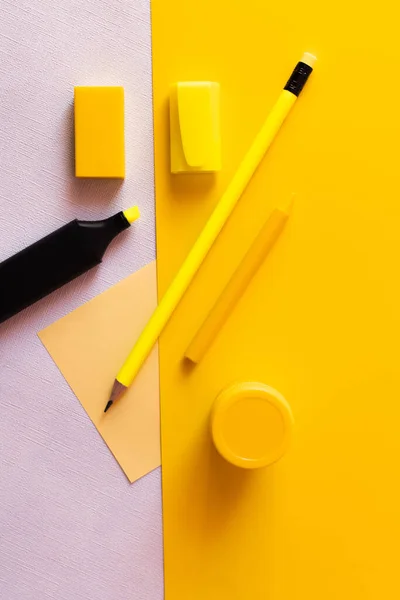 Top view of stationery and marker pen near paper note on yellow and white — стоковое фото