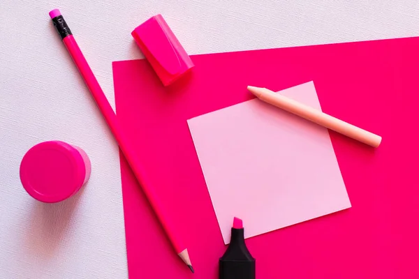 Vue du dessus de la papeterie et du pot avec peinture près de la note de papier vierge sur blanc texturé et rose — Photo de stock