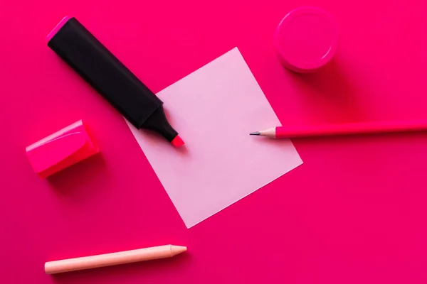 Papeterie in der Nähe von Glas mit Farbe und leerem Zettel auf rosa — Stockfoto