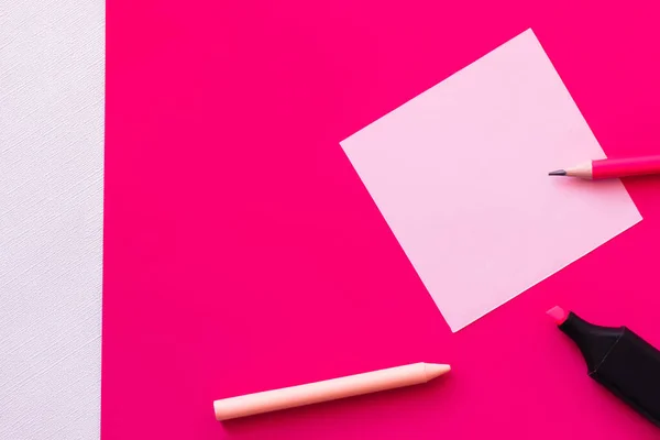 Vista dall'alto della cancelleria vicino nota di carta bianca su texture bianco e rosa — Foto stock