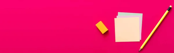 Top view of pencil and eraser near multicolored paper notes on pink background, banner — стоковое фото