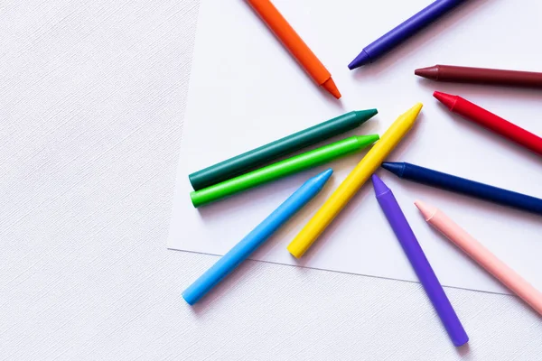 Top view of colorful crayons on white paper and textured background — Stock Photo